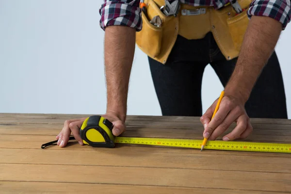 Architect measuring wooden plank with tape measure — Stock Photo, Image