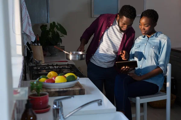 Casal usando comprimido enquanto cozinha — Fotografia de Stock