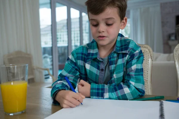 Jongen doet huiswerk aan tafel — Stockfoto