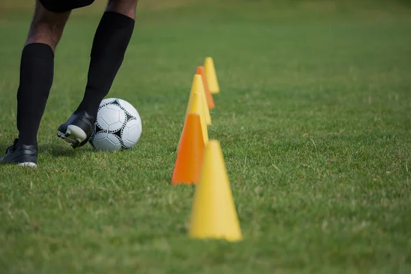 Joueur de football dribble à travers les cônes — Photo