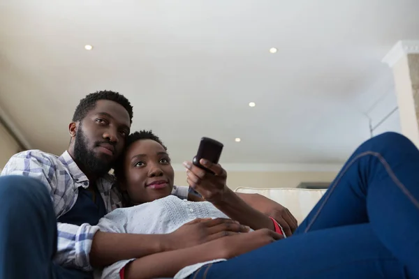 Par titta på TV tillsammans i vardagsrummet — Stockfoto