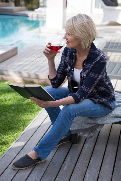 Woman reading book while drinking wine — Stock Photo, Image