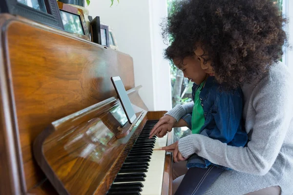 Mor medhjälpande dotter spela piano — Stockfoto