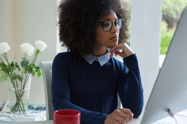 Femme réfléchie travaillant sur PC de bureau — Photo