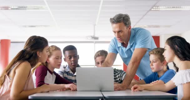 Teacher assisting schoolkids on laptop — Stock Video