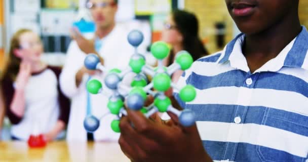 Schoolboy examining molecule model — Stock Video