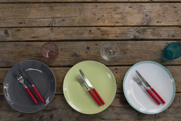 Platos con tenedor, cuchillo de mantequilla y vidrio en la mesa — Foto de Stock