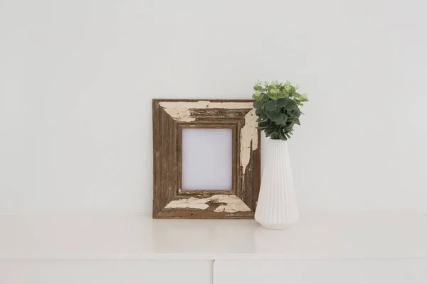 Moldura de madeira e vaso contra a parede branca — Fotografia de Stock