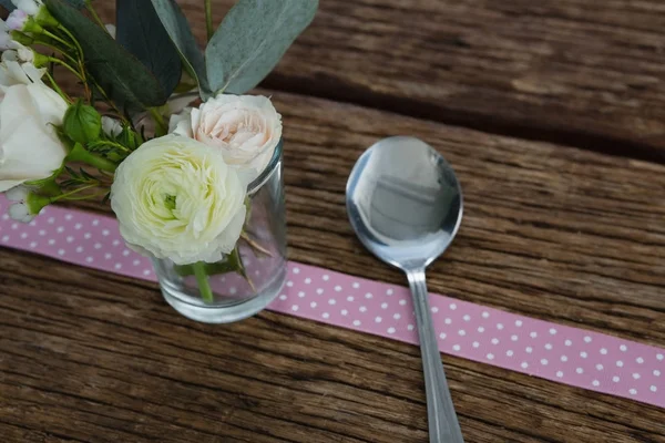 Rosa blomma med sked och band på tabell — Stockfoto
