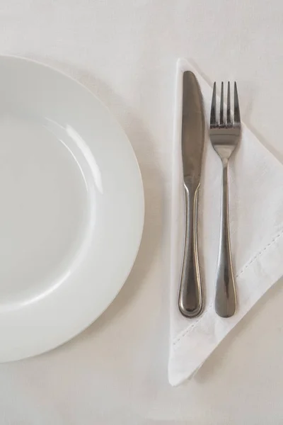 Placa blanca y cubiertos en una mesa — Foto de Stock