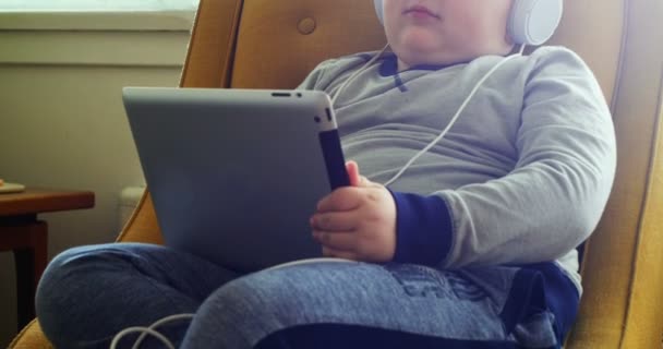 Niño en auriculares usando tableta digital — Vídeos de Stock