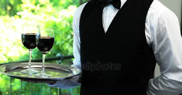 Чоловічий офіціант тримає піднос з келихами для вина — стокове відео