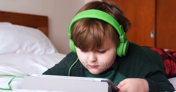 Хлопчик в навушниках за допомогою цифрового планшета — стокове відео