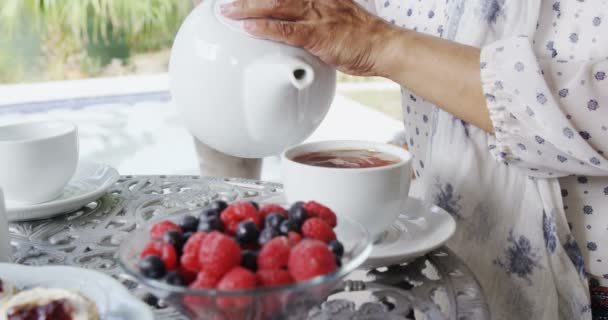 Зрелая женщина наливает чай в чашку — стоковое видео