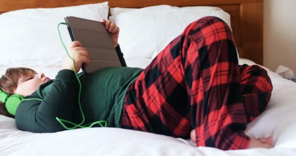 ホームの で寝室にデジタル タブレットを使用してヘッドフォンの少年 — ストック動画