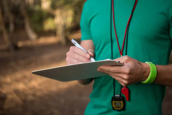 Trainer holding notepad in hands in forest — Stock Photo, Image