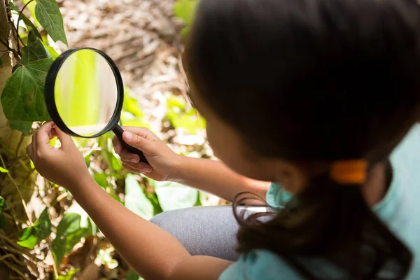Menina explorando a natureza através de lupa — Fotografia de Stock
