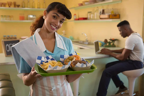 Serveuse tenant le petit déjeuner pendant que l'homme travaille — Photo