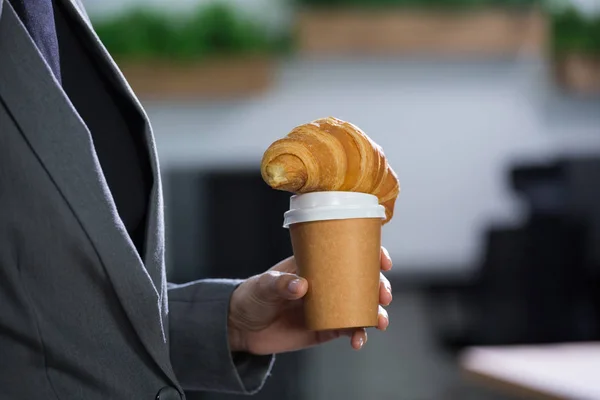 Executivo feminino segurando café e croissant — Fotografia de Stock