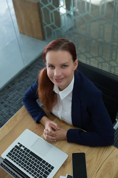 Female executive sitting with laptop at desk — Stock Photo, Image