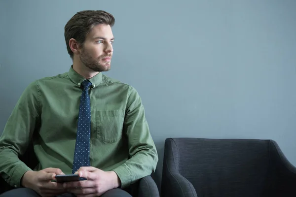 Executivo masculino sentado com telefone móvel — Fotografia de Stock