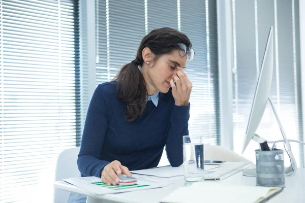 Tired female executive sitting at desk — Stock Photo, Image