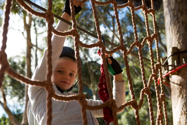 Niña con arnés de seguridad trepando valla de cuerda — Foto de Stock