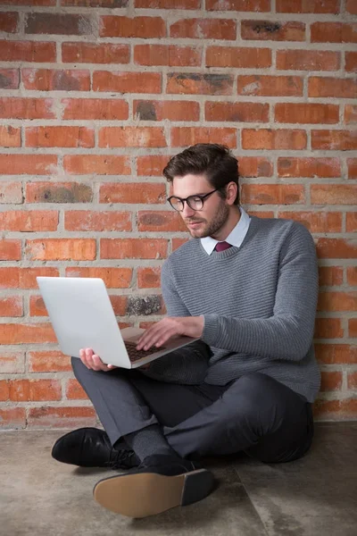 Executive using laptop against brick wall — Stock Photo, Image