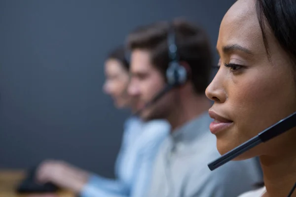 Ejecutiva femenina con auriculares usando computadora —  Fotos de Stock