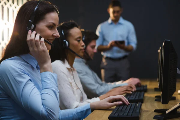 Cadres d'entreprise avec écouteurs utilisant des ordinateurs — Photo