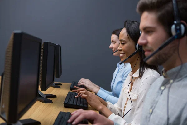 Företagsledare med headset använder datorer — Stockfoto