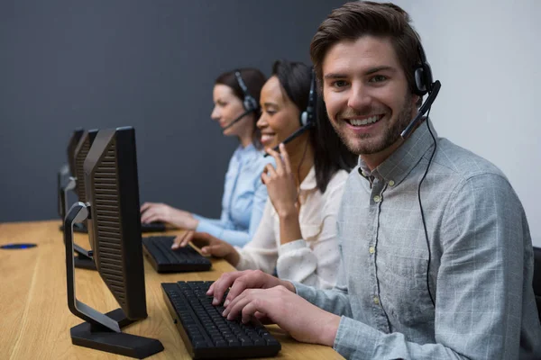 Bedrijfsleiders met headsets met behulp van computers — Stockfoto