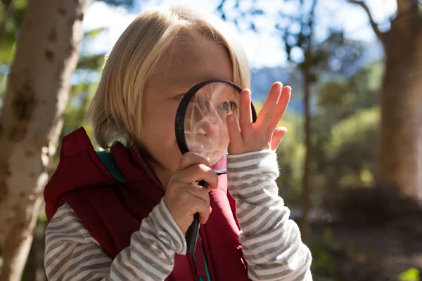 Girl looking at hand through magnifying glass — Stock Photo, Image