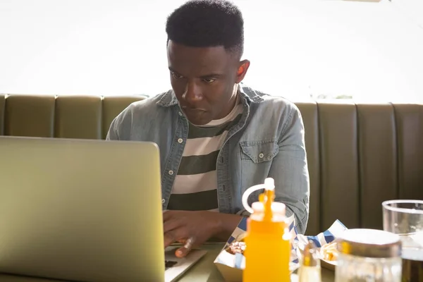 Młody człowiek siedzi na kanapie przy użyciu laptopa — Zdjęcie stockowe