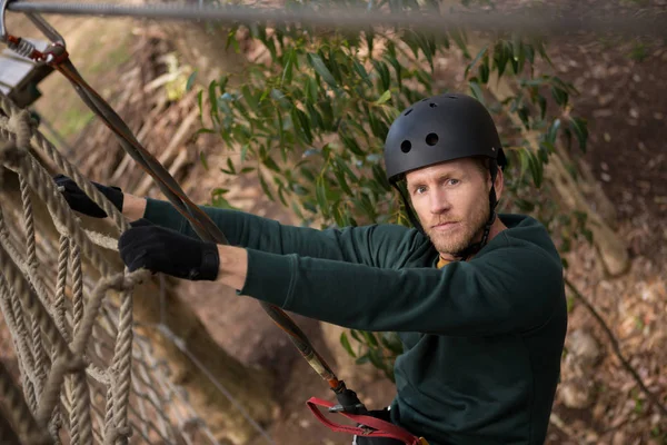 Männlicher Wanderer mit Helm klettert Seilzaun — Stockfoto
