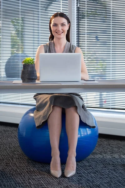 Female executive sitting on exercise ball — Stock Photo, Image