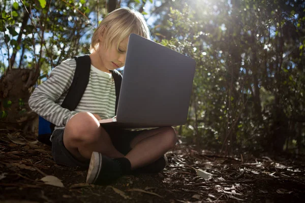 Dziewczynka z plecakiem siedzi na ziemi za pomocą laptopa — Zdjęcie stockowe