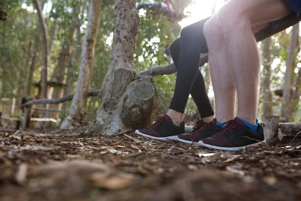 Man and woman sitting on log of wood — Stock Photo, Image