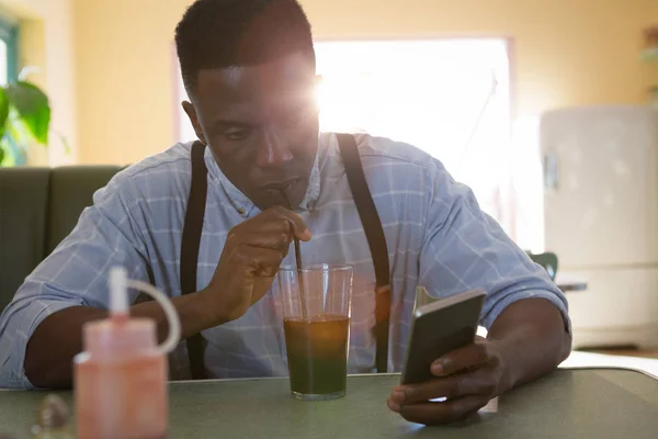 Hombre usando el teléfono móvil mientras toma bebidas — Foto de Stock