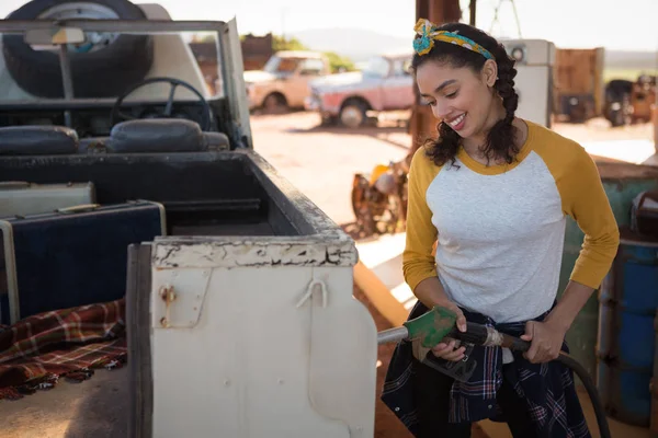 Женщина, заправляющая машину бензином на бензоколонке — стоковое фото