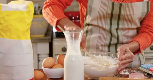近距离的女人穿着围裙倒入牛奶的混合物在厨房4K — 图库视频影像