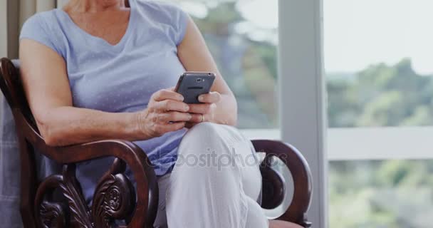 ホームの で携帯電話を使用して満足している年配の女性 — ストック動画