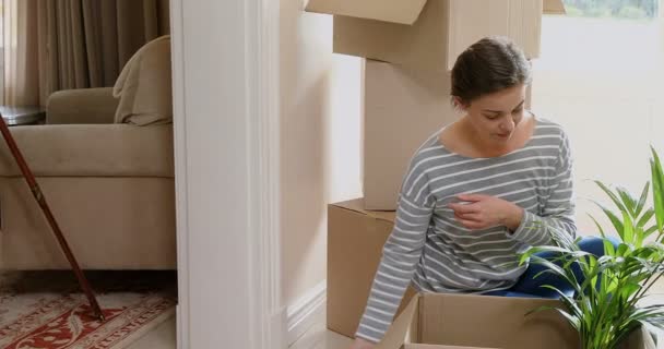 Женщина Распаковывает Картонную Коробку После Переезда Новый Дом — стоковое видео