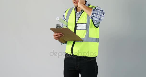 クリップボードを保持していると を白背景携帯電話で話している男性建築家 — ストック動画