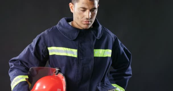 Feuerwehrmann Mit Helm Der Hand Vor Schwarzem Hintergrund — Stockvideo
