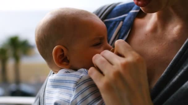 Young Mother Consoling Crying Baby Sling Home Sunny Day — Stock Video