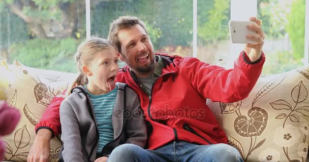 Feliz Padre Hija Sentados Sofá Haciendo Caras Divertidas Mientras Toman — Vídeos de Stock