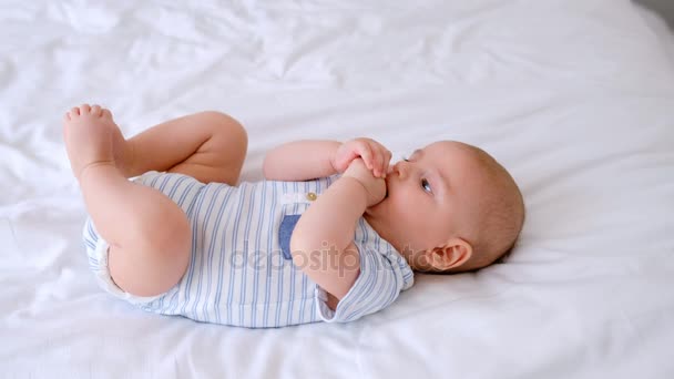Bonito Bebê Mastigar Mãos Deitado Cama Quarto Casa — Vídeo de Stock