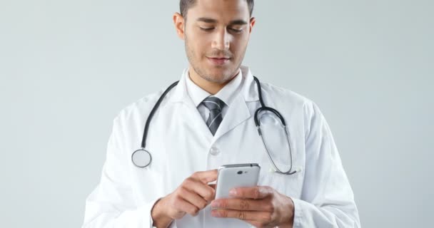 Médico Sonriente Usando Teléfono Inteligente Contra Fondo Blanco — Vídeos de Stock