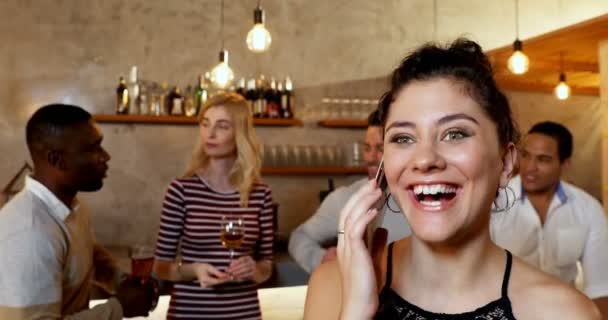Jovem Sorrindo Mulher Falando Telefone Enquanto Amigos Interagindo Segundo Plano — Vídeo de Stock